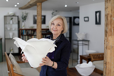 Angela Mellor in the gallery holding a large paperclay sculpture